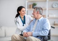 Impaired senior man in wheelchair and young nurse taking care of him at home Royalty Free Stock Photo