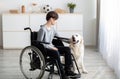 Impaired teenager in wheelchair stroking his cute golden retriever at home. Domestic animals therapy concept