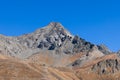 Impassable granite raven vertical mountainside and tipped rocks with black top peak under background of clear blue sky Royalty Free Stock Photo