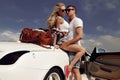 Impassioned couple in casual clothes, posing beside luxurious car