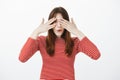 Impatient excited woman peeking through fingers. Indoor portrait of intrigued amazed caucasian female student, closing