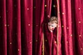 Impatient young actor peeking out from the curtain