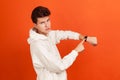Impatient young man in stylish white sweatshirt with serious face pointing his finger on handwatch, time to act, deadline Royalty Free Stock Photo