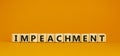 Impeachment symbol. Wooden cubes with the word `impeachment`. Beautiful orange background, copy space. Business, impeachment