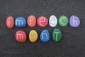 Impeachment word composed with multi colored sea stones over black volcanic sand