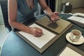 Impersonal woman drawing in a notebook behind the table