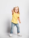 Impish kid baby girl in yellow t-shirt is playing dancing having fun good time showing thumb up sign feeling great Royalty Free Stock Photo