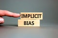 Implicit bias symbol. Concept words Implicit bias on wooden block. Beautiful grey table grey background. Businessman hand.
