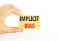 Implicit bias symbol. Concept words Implicit bias on wooden block. Beautiful white table white background. Businessman hand.