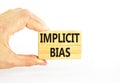 Implicit bias symbol. Concept words Implicit bias on wooden block. Beautiful white table white background. Businessman hand.