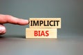 Implicit bias symbol. Concept words Implicit bias on wooden block. Beautiful grey table grey background. Businessman hand.