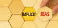 Implicit bias symbol. Concept words Implicit bias on wooden puzzles. Beautiful yellow table yellow background. Businessman hand.