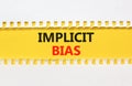 Implicit bias symbol. Concept words Implicit bias on yellow paper. Beautiful yellow table white background. Business psychology