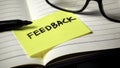 Importance of Constructive Feedback: Yellow Reminder Note on Open Notebook Royalty Free Stock Photo