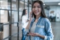 Important business talk. Beautiful young asian woman talking on the mobile phone and smiling while standing in modern office Royalty Free Stock Photo