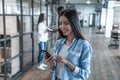 Important business talk. Beautiful young asian woman talking on the mobile phone and smiling while standing in modern office Royalty Free Stock Photo