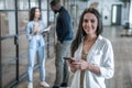 Important business talk. Beautiful young asian woman talking on the mobile phone and smiling while standing in modern office Royalty Free Stock Photo