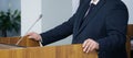 An important man - a lawyer, businessman, politician, or official speaks to the public, leaning his hands on the podium. Official