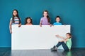 An important message brought to you by the kids. Studio portrait of a diverse group of kids standing behind a large Royalty Free Stock Photo