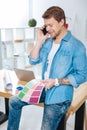 Creative designer holding color palettes while talking on the phone