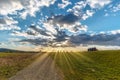 An imposing cloud sky in a landscape of fields and a path where sun rays Royalty Free Stock Photo