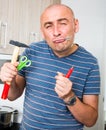 Imposing man in prime of life holds in teeth of screws and holding hammer