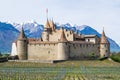 Imposing medieval Aigle castle atop a small hill, surrounded by majestic snow-capped mountain peaks