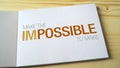 Impossible becomes possible by fading letters printed on the notebook page.