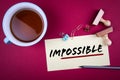 Impossible. Word possible underlined with a red stripe. Teacup, pencil and stamps on the table Royalty Free Stock Photo