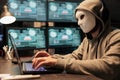 Impostor with mask hacking computer network at night