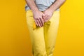 Impotence and men`s health. A man in yellow jeans shyly covers a banana near the genitals with his hands. Yellow background. Clos