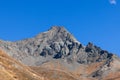 Impregnable granite black steep mountainside and sharp rocks with top peak under background of clear blue sky Royalty Free Stock Photo