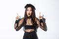 Impressed asian girl in black lace dress and wreat turn your attention on halloween promo, making announcement, pointing