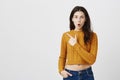 Impressed cute european woman standing with opened mouth and pointing at upper left corner, wearing cropped sweater Royalty Free Stock Photo