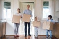 Impressed family carrying boxes moving in to new house Royalty Free Stock Photo