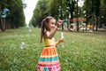 Impressed little girl blows bubbles in the park.