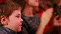 Impressionable little boy sits on a red chair in