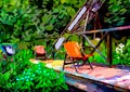 An impressionist painting style image of a garden with walkway bridge, chairs and plants