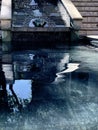 Impressionistic photo of small gargoyle in a water fountain with a reflecting pool.