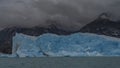 An impressive blue glacier against the mountains and fog. Royalty Free Stock Photo