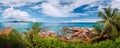 Impressive cloudscape panorama of La Digue wild rocky shore and Praslin Island on horizon. Seychelles. Royalty Free Stock Photo