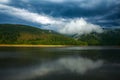 Impressive landscape of green coniferous mountains above lake against the background of stormy gray clouds, rainy weather, Ukraine Royalty Free Stock Photo