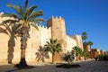 The impressive ramparts of the medina surrounded by colorful palmtrees and a large cobbled walkway in Sfax