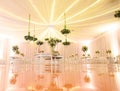 IMPRESSIVE RECEPTION VENUE WITH BEAUTIFUL WHITE  WEDDING CAKE AT CANDY TABLES, FLORAL GREEN DECORATION, REFLECTIVE FLOOR, BLURRED Royalty Free Stock Photo