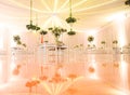 IMPRESSIVE RECEPTION VENUE WITH BEAUTIFUL WHITE  WEDDING CAKE AT CANDY TABLES, FLORAL GREEN DECORATION, REFLECTIVE FLOOR, BLURRED Royalty Free Stock Photo