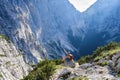 Impressive scale of mountains in Triglav National Park, Slovenia. Woman on via ferrata sits on a rock and points up Royalty Free Stock Photo