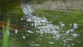 An old wide tube with water falling into a lake in slo-mo