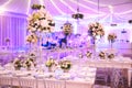 IMPRESSIVE VIOLET RECEPTION VENUE WITH BEAUTIFUL FLORAL GREEN DECORATION,  WHITE TABLES, BLURRED BACKGROUND, YELLOW LIGHTS, AND BL Royalty Free Stock Photo