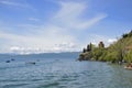 Impressively beautiful view from lake with boats tree, stones, beach, mountain on clear blue sky