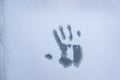 Imprint of a human palm on a frozen window glass inspires fear and horror